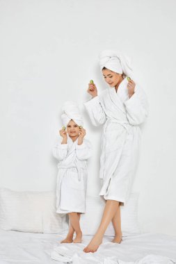 Mutlu kadın ve kızı taze salatalık dilimleri tutuyor.