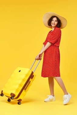 Bavullu kadın sarı arka planda seyahat ediyor..