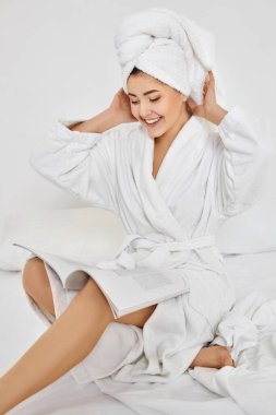 Beyaz bornozlu hoş bir kadın dergi okuyor.