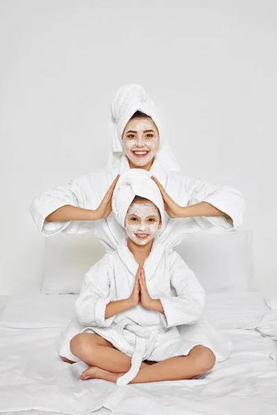 Matka a dcera sedí s ručníky na hlavě a obličejové masce. — Stock fotografie