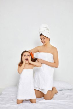 Anne kızının saçını tarıyor.