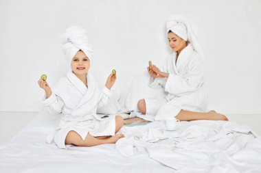 Küçük kız elinde salatalık dilimleri ve elinde tırnak törpüsü tutuyor.