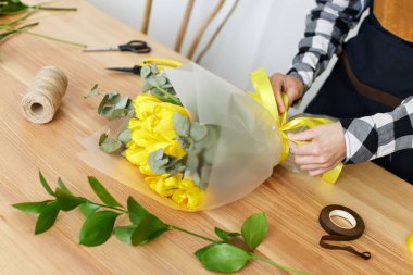 Çiçekçi taze sarı lalelerden bir buket yapar..