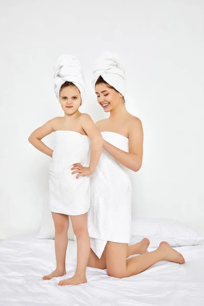 Schöne Mutter und Tochter in weißen Bademänteln und Handtüchern — Stockfoto
