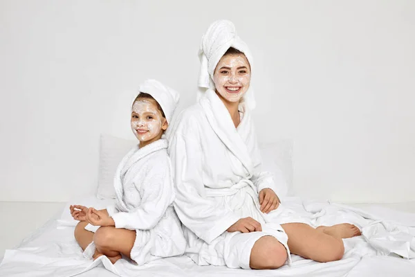 Matka i córka siedzą z ręcznikami na głowie i maską na twarzy. — Zdjęcie stockowe