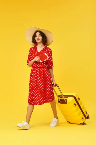 Frau mit Koffer auf Reisen auf gelbem Hintergrund. — Stockfoto