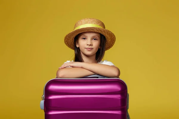 Dziecko z różową walizką na żółtym tle. — Zdjęcie stockowe