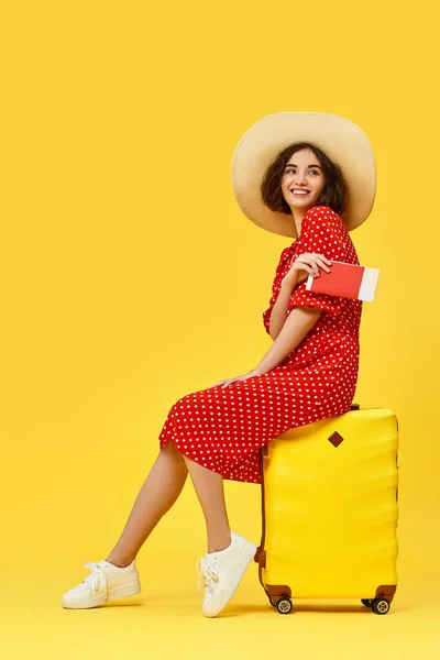 Frau mit Koffer auf Reisen auf gelbem Hintergrund. — Stockfoto