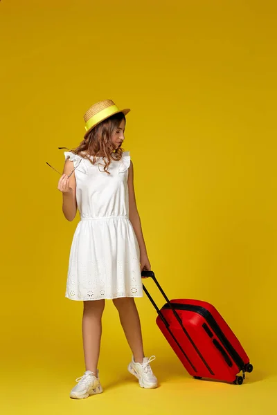 Nastolatka dziewczyna w kapeluszu i okulary z czerwoną walizką — Zdjęcie stockowe