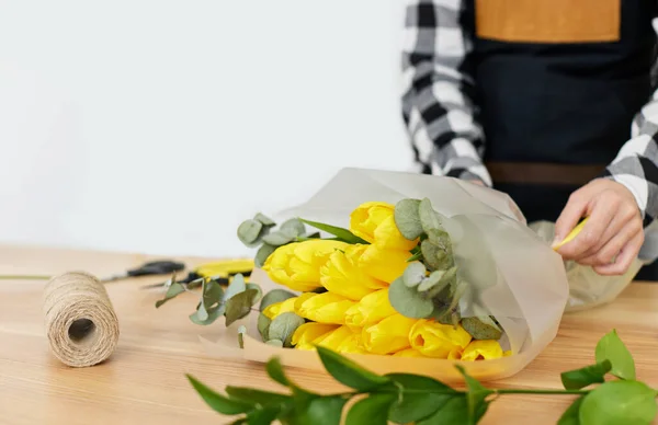 Florist makes a bouquet of fresh yellow tulips.