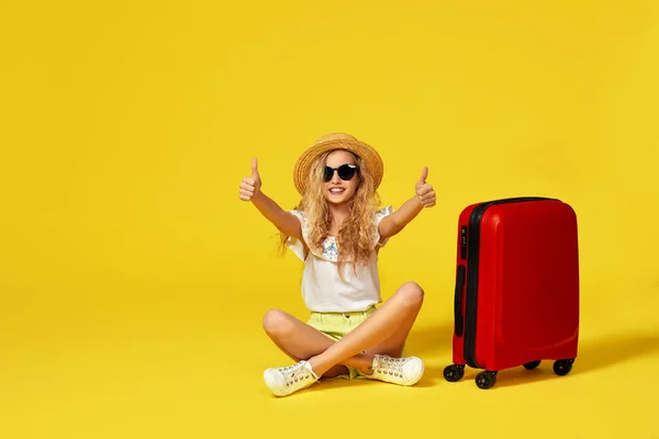 Збуджена маленька дівчинка з валізою і паспортом сидить на підлозі — стокове фото