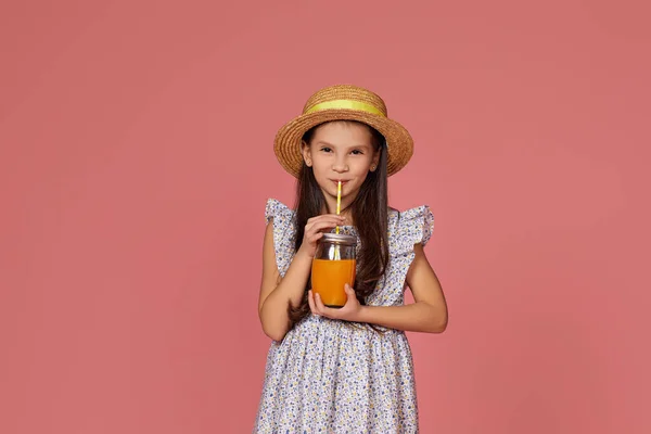 Linda niña en sombrero con jugo de naranja —  Fotos de Stock