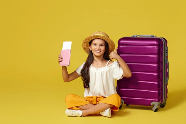 Маленька дівчинка з валізою і паспортом сидить на підлозі — стокове фото