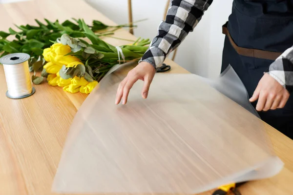 Bloemist maakt een boeket van verse gele tulpen. — Stockfoto