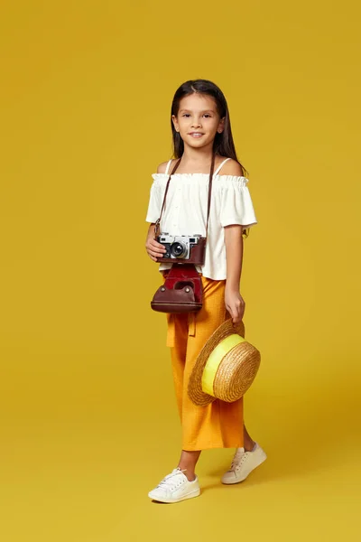 Linda niña con cámara retro sobre fondo amarillo. —  Fotos de Stock