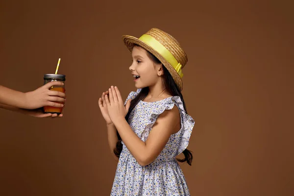 Alguien le da un vaso de jugo de naranja a una linda niña —  Fotos de Stock
