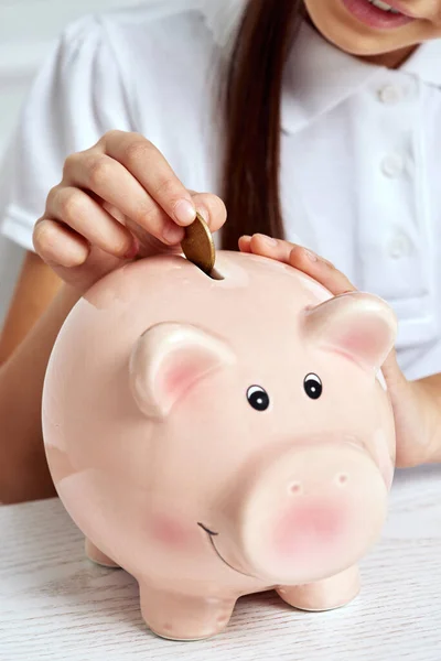 Child girl putting coin into pink piggy bank. — Stock Photo, Image