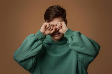 Üzgün, ağlayan, yeşil tişörtlü genç adam.