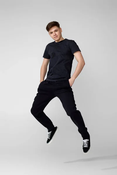 검은 티셔츠 점프를 하는 잘생긴 청년. — 스톡 사진