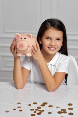 Evinde domuz kumbarası olan küçük bir kız.