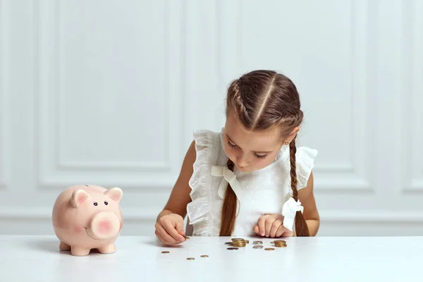 Menina criança com banco porquinho em casa — Fotografia de Stock