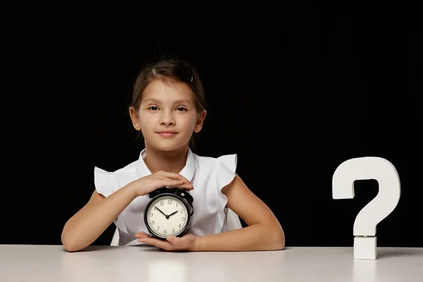 Gelukkig schoolmeisje met wekker zitten aan tafel — Stockfoto