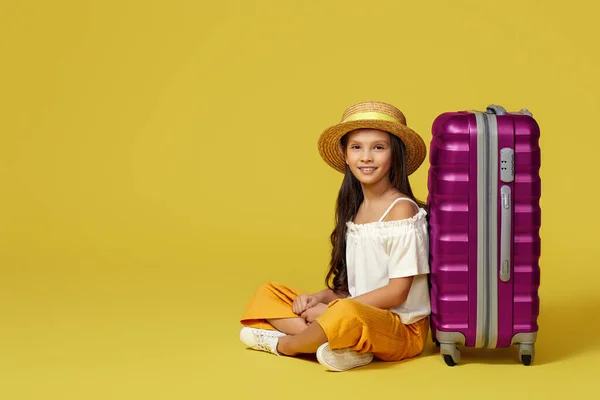 Kislány bőrönddel és útlevéllel ül a földön — Stock Fotó