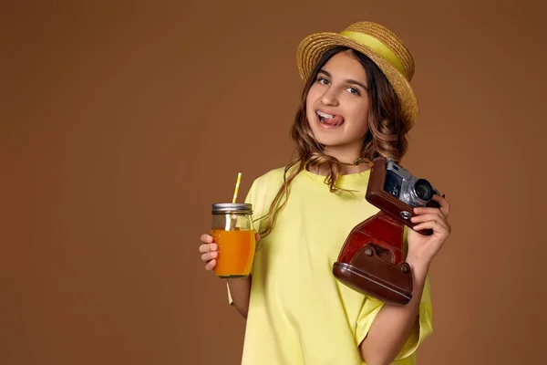 Chica atractiva en sombrero con jugo de naranja y cámara retro —  Fotos de Stock