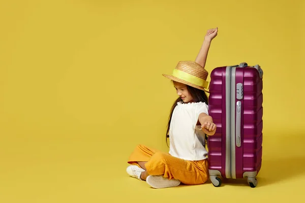 Kleines Mädchen mit Koffer und Reisepass auf dem Boden sitzend — Stockfoto