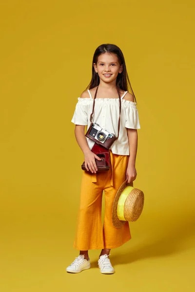 Linda niña con cámara retro sobre fondo amarillo. —  Fotos de Stock
