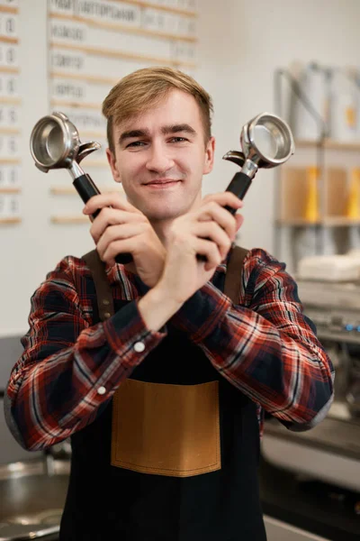 Happy male waiter holding two holders for a coffee machine — Stock Photo, Image