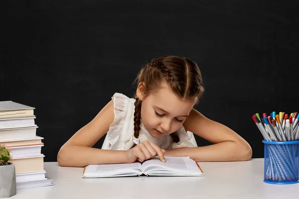 Menina criança lendo um livro na sala de aula — Fotografia de Stock
