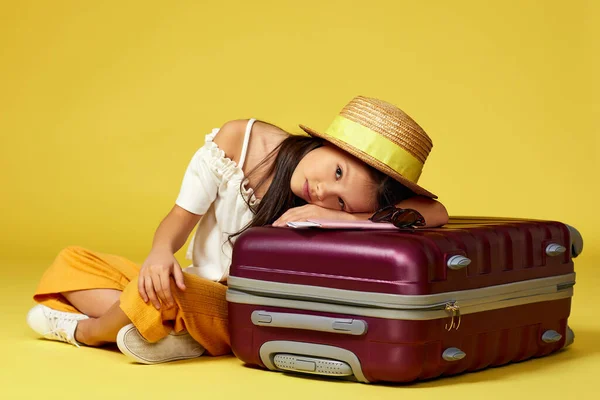 Dziewczynka z walizką i paszportem siedząca na podłodze — Zdjęcie stockowe
