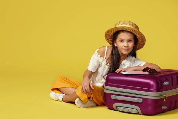 Dziewczynka z walizką i paszportem siedząca na podłodze — Zdjęcie stockowe