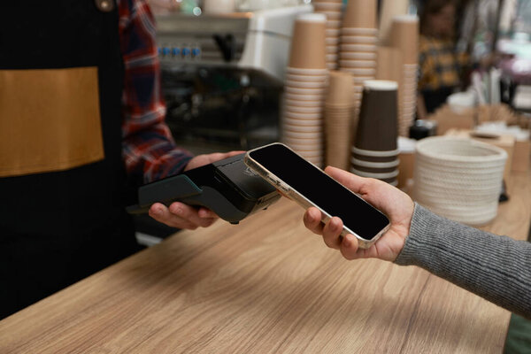 customer holding phone near nfc terminal make contactless payment.