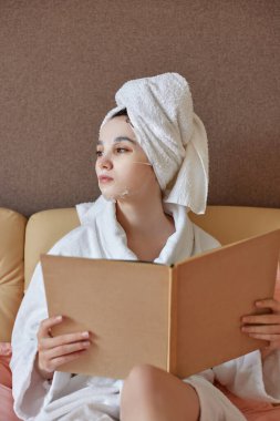 Beyaz bornozlu, kafasında havlu olan beyaz bir kadın.