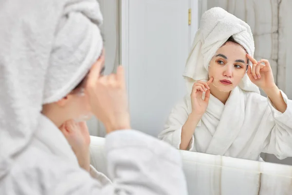 Mulher de roupão branco na frente do espelho no banheiro — Fotografia de Stock