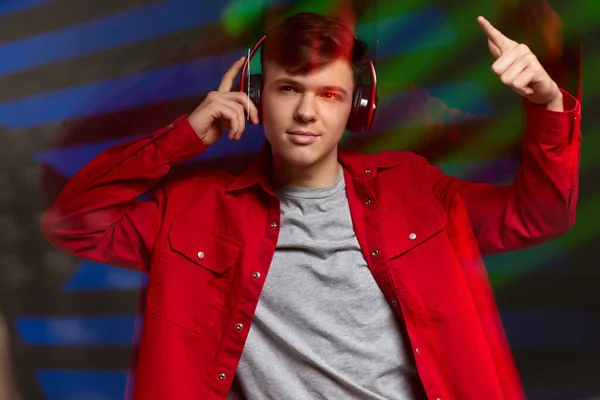 Νεαρός άνδρας με κόκκινο πουκάμισο με ακουστικά ακούγοντας μουσική — Φωτογραφία Αρχείου