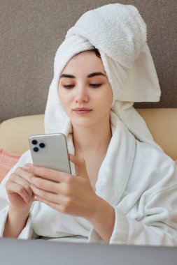 Beyaz bornozlu, kafasında havlu olan beyaz bir kadın.