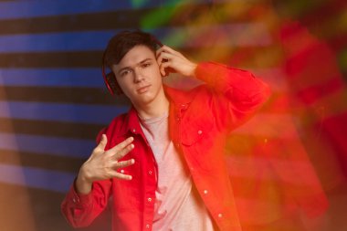 Kırmızı gömlekli, kulaklıklı, müzik dinleyen genç bir adam.