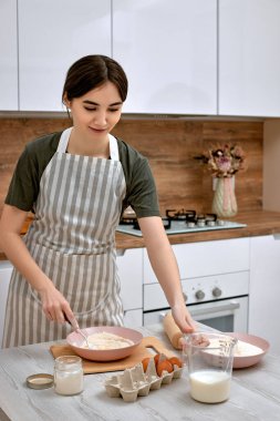 Genç ve güzel ev hanımı mutfakta yemek pişiriyor..