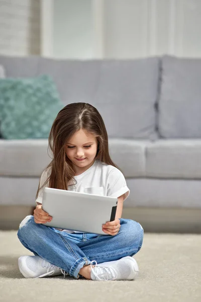 Malá holčička dívá na tablet doma — Stock fotografie