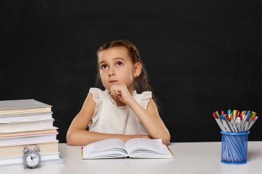 Sınıftaki masada oturan mutlu kız öğrenci.