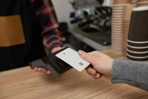 customer hand holding credit card near nfc terminal.