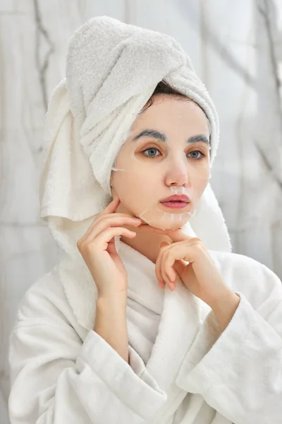 Mulher de roupão branco na frente do espelho no banheiro — Fotografia de Stock