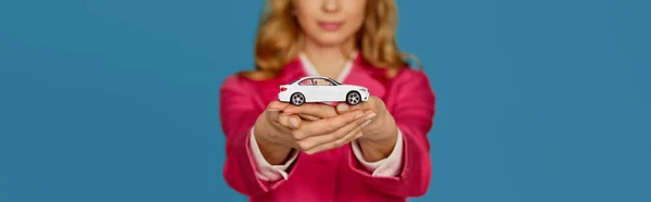 Piękna blondynka w różowej kurtce trzyma mały samochód — Zdjęcie stockowe
