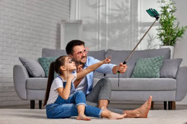 Baba ve çocuk ellerinde kağıt bardaklarla selfie çekiyorlar.