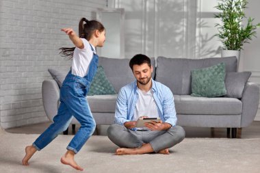 Çocuk babası dizüstü bilgisayarla uğraşırken koşuyor.