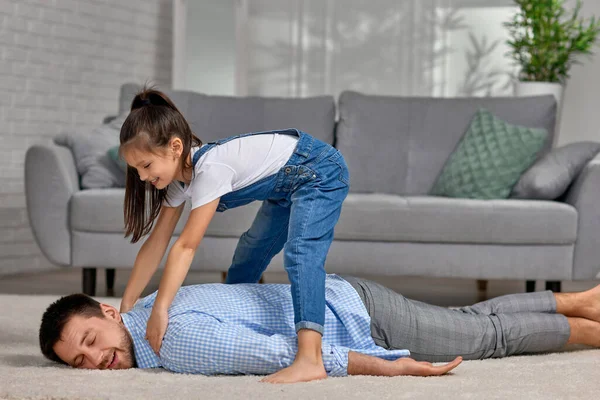 Happy little child daughter doing massage to father — Stock Photo, Image