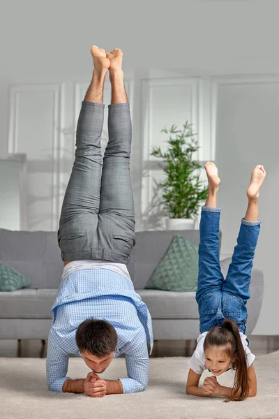 Far kopiera imitera aktiv barn flicka gör gymnastiska handstand motion — Stockfoto